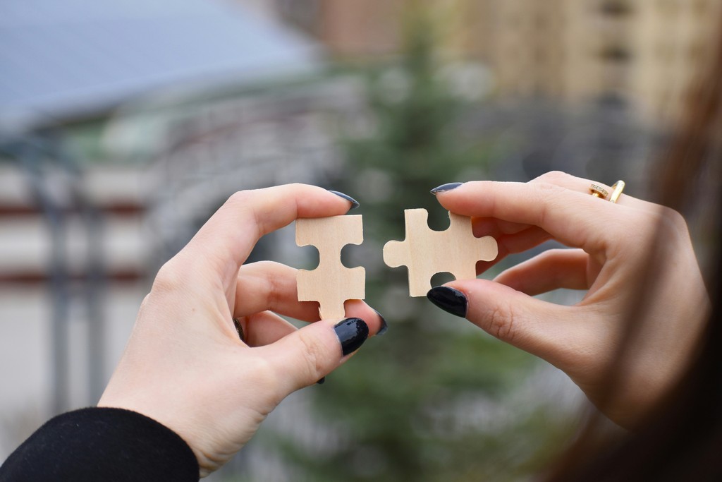 Two hands joining complementary puzzle pieces