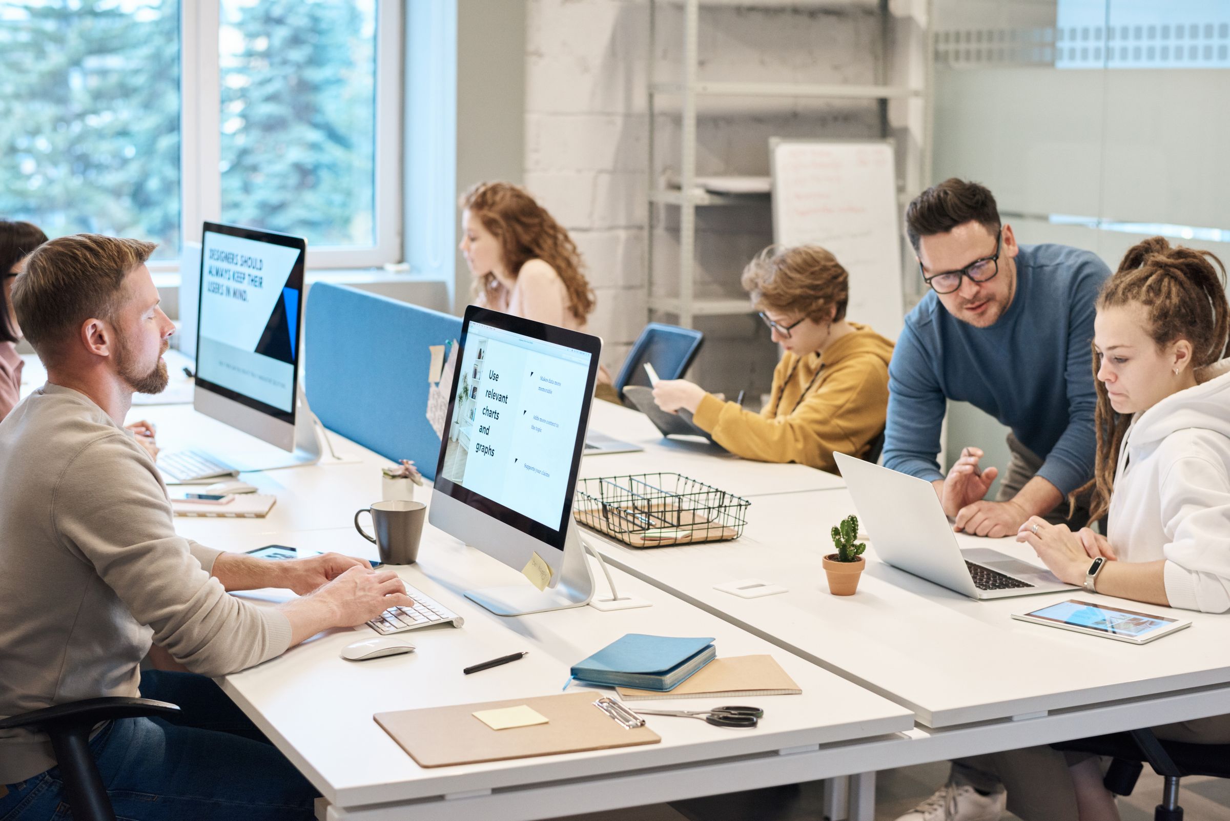 Colleagues supporting each other at shared office workstations